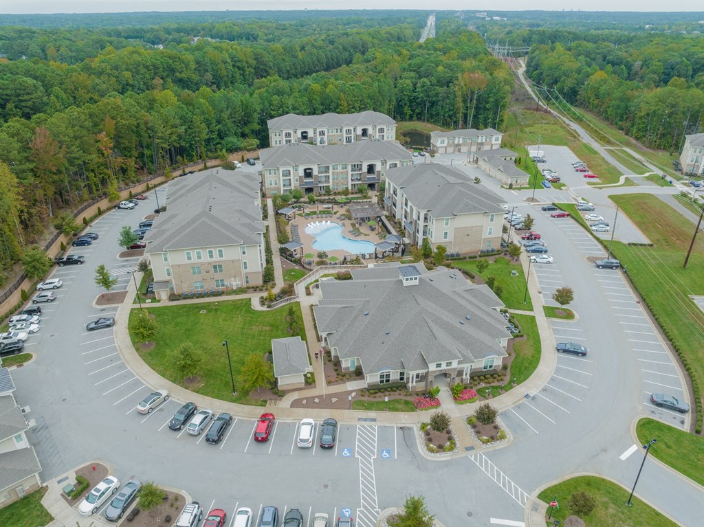 an aerial view of an apartment complex with parking lot and cars