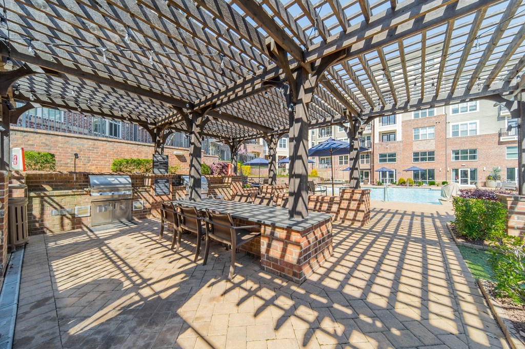 a pergola with a table and chairs on a brick patio