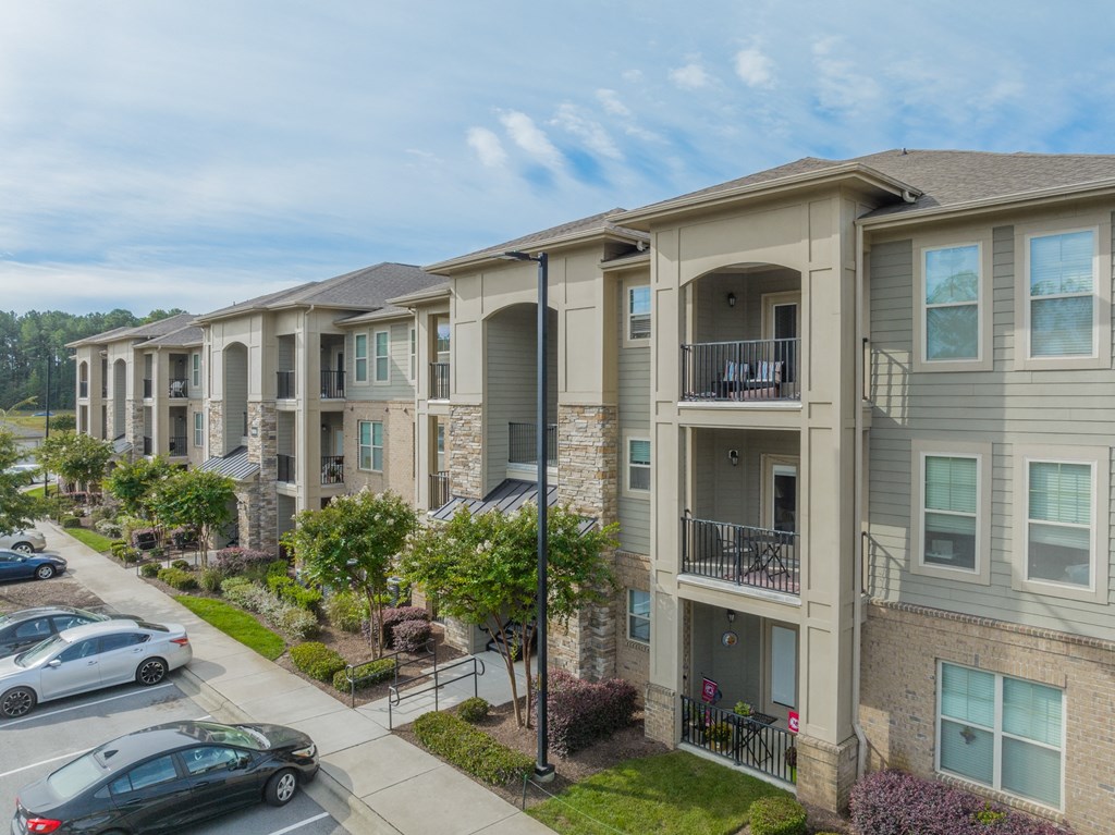 a row of apartment buildings with cars parked outside