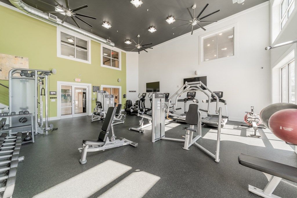 a spacious fitness center with exercise equipment and windows