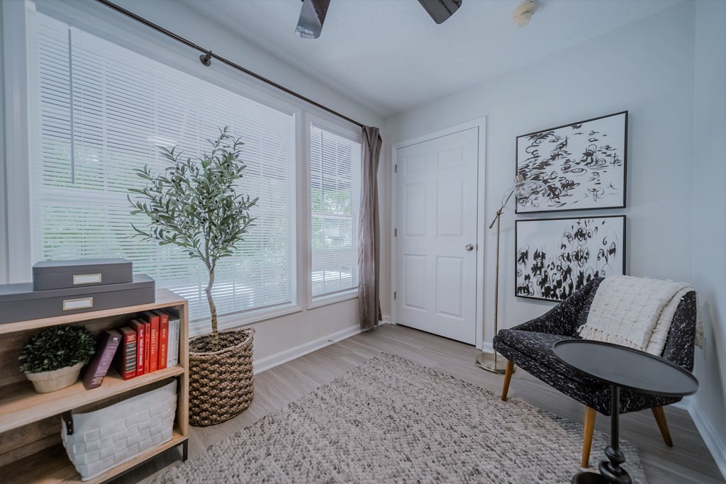 a living room with large windows and a chair and a rug