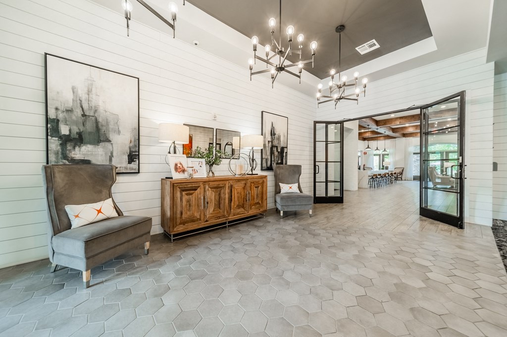 the lobby of a home with two chairs and a wooden cabinet