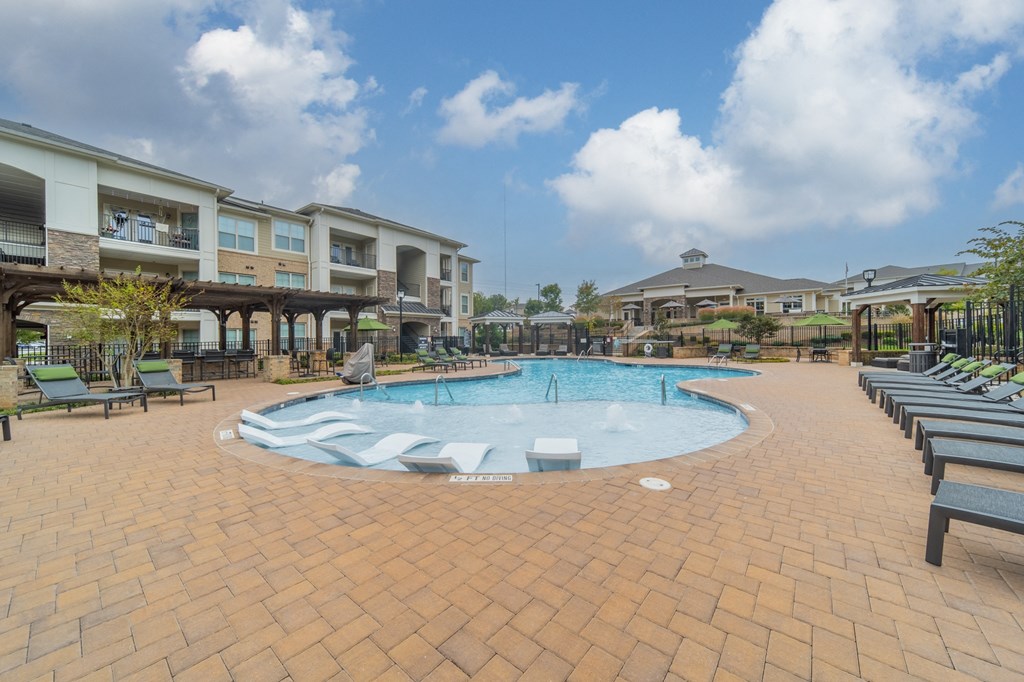 a resort style pool with lounge chairs and buildings in the background