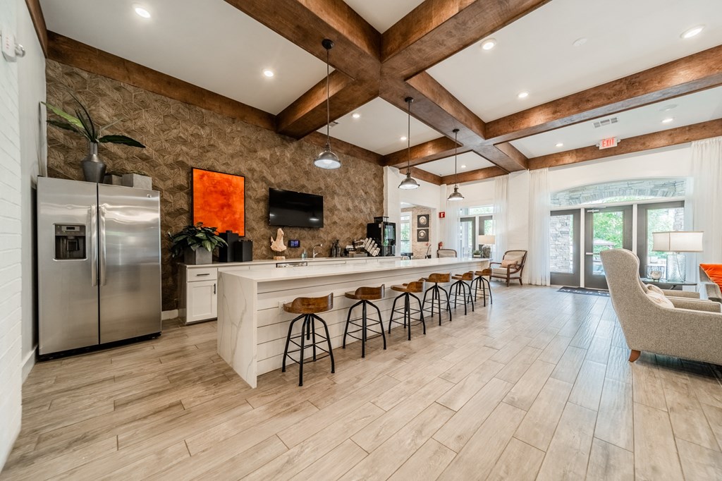 a kitchen with a long island with bar chairs and a refrigerator