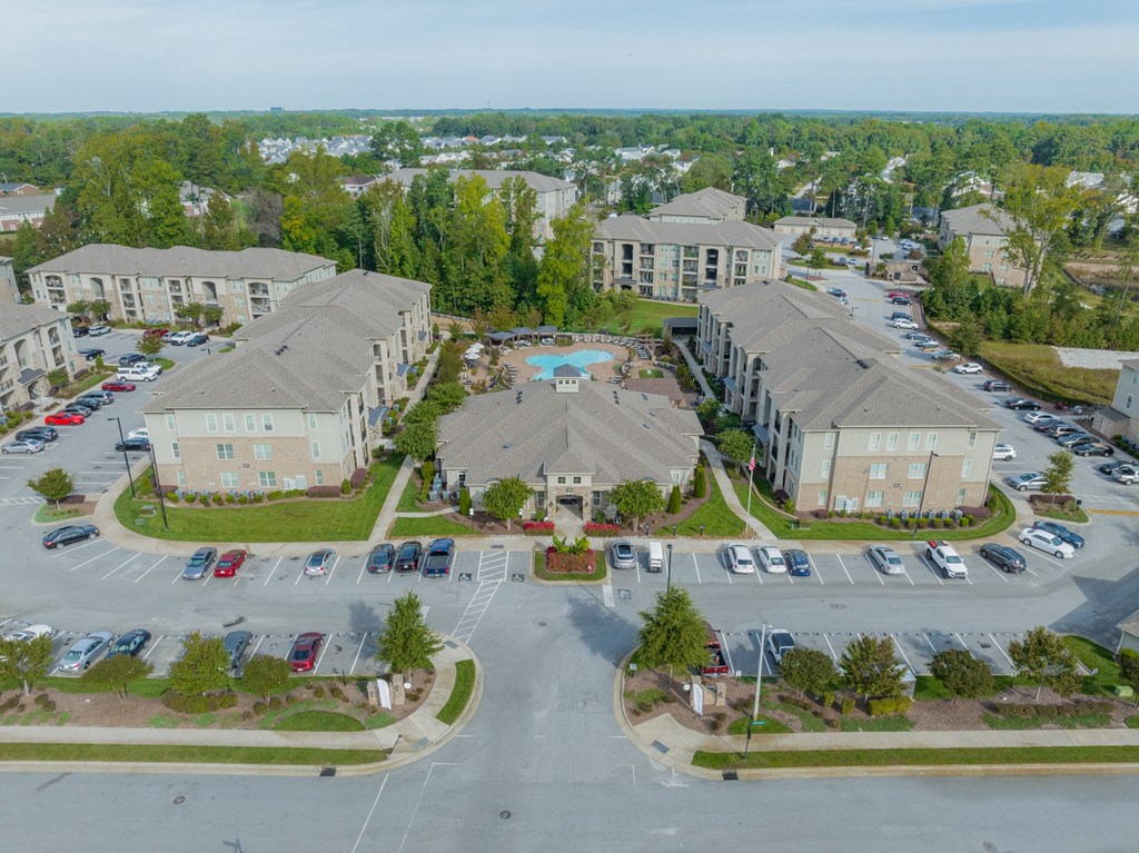 an aerial view of an apartment complex with a swimming pool and parking lot