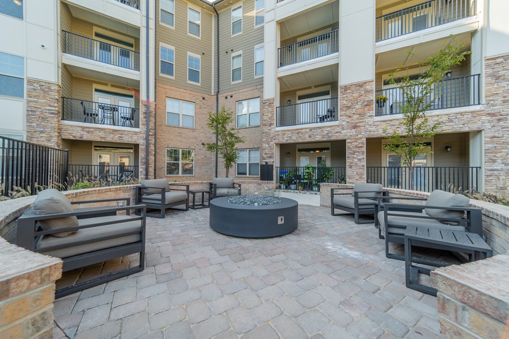 an outdoor patio with a fire pit in front of an apartment building