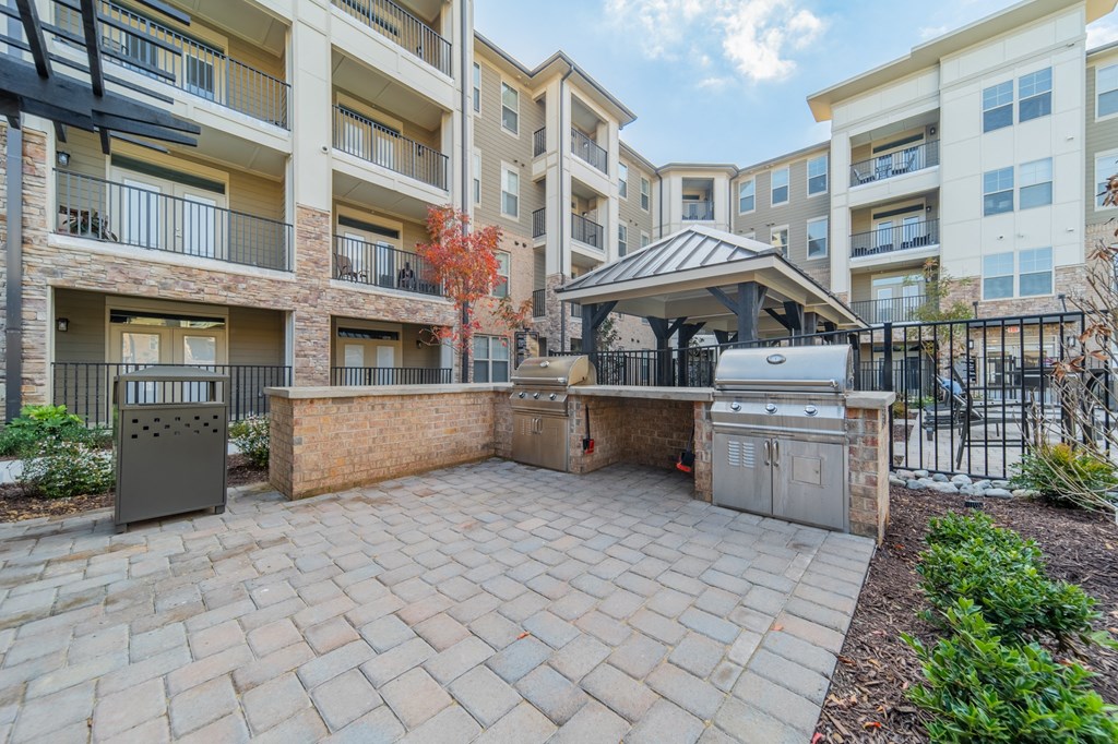 an outdoor kitchen with a grill and a gazebo in an apartment complex