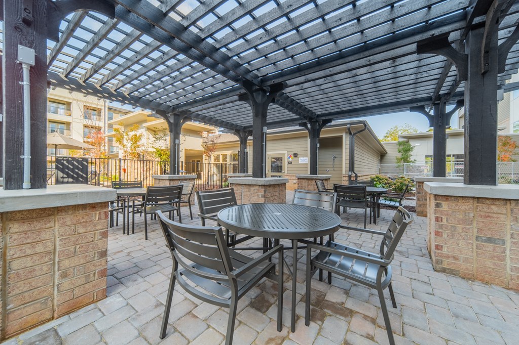 a patio with tables and chairs under a pergola