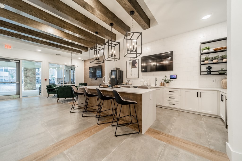 a kitchen with a long island with bar stools and exposed wood beams