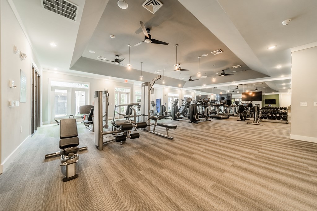 a gym with cardio equipment and weights on a wooden floor