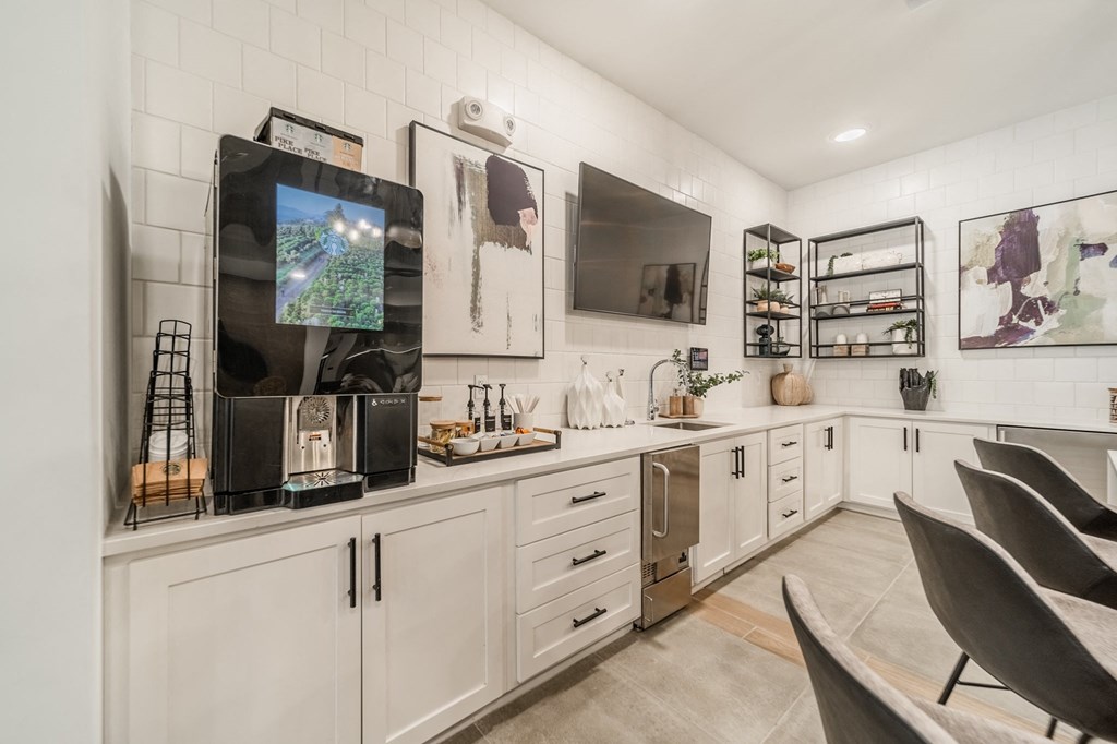a kitchen with white cabinets and a tv on the wall