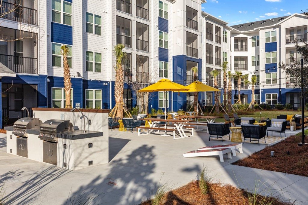 a courtyard with tables and umbrellas in front of an apartment building