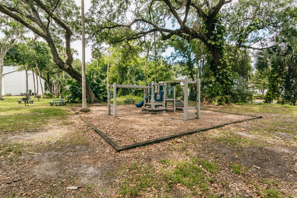 a playground with a swing set in a park with trees