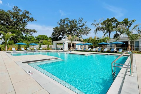 A large swimming pool with a metal railing and a building in the background.