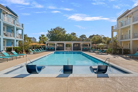 A large swimming pool with lounge chairs and a building in the background.