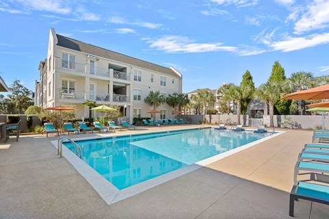A large swimming pool in front of a multi-story apartment building.