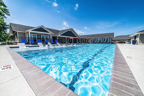 A large outdoor swimming pool with a wooden deck and sun loungers.
