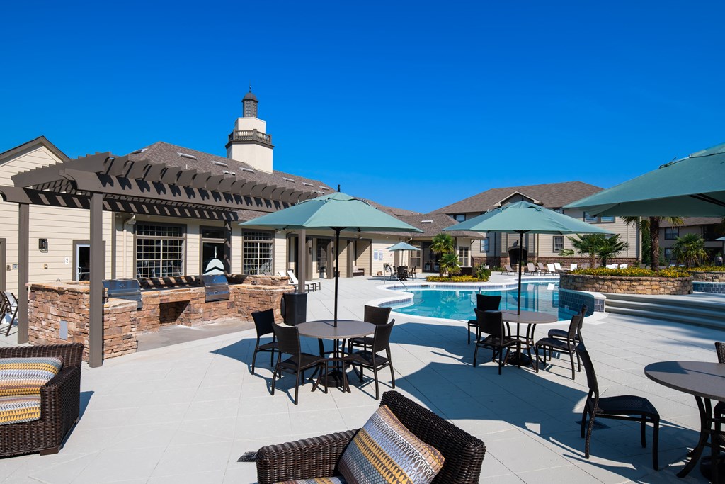 a patio with tables and umbrellas and a swimming pool