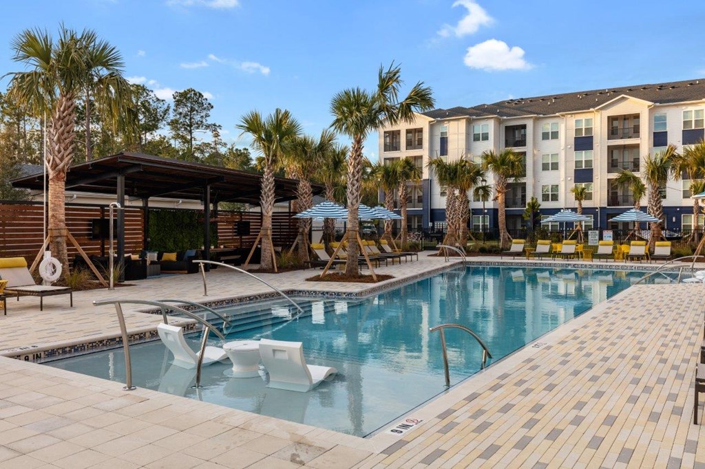 a large pool with chairs and a building in the background