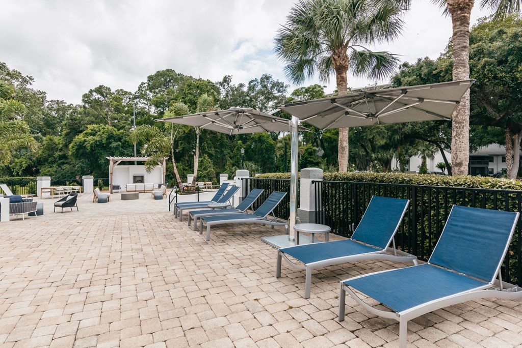 a group of lounge chairs and umbrellas on a brick patio