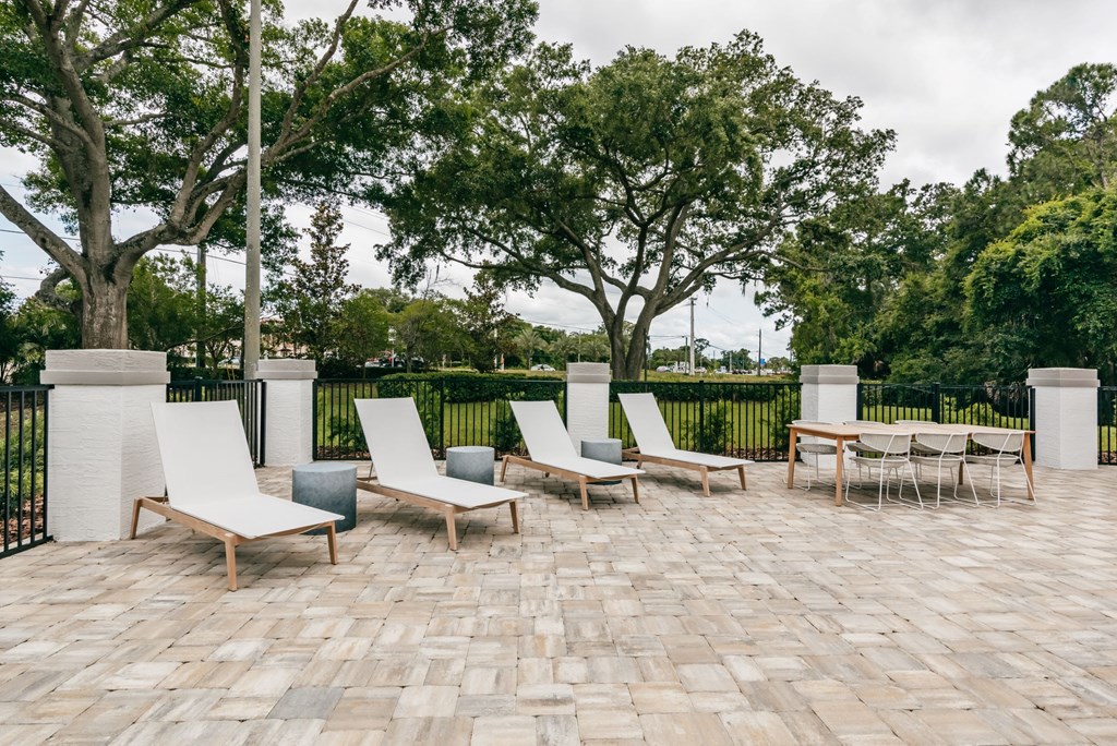 a patio with lounge chairs and tables and trees