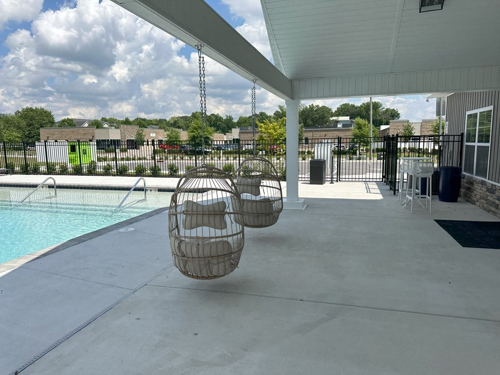a patio with two hammock chairs and a swimming pool
