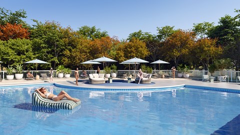 A woman lounges on a float in a pool surrounded by trees.