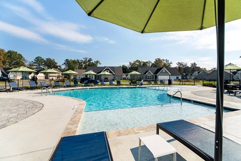 A pool with a green umbrella in the foreground.
