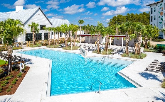 a large swimming pool with chairs and palm trees