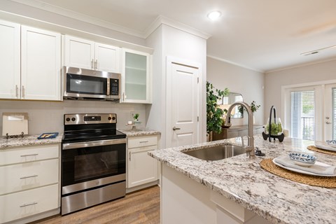 a kitchen with white cabinets and granite counter tops and stainless steel appliances