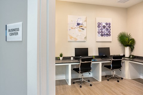 a business center with three desks and chairs and paintings on the wall
