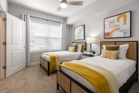 two beds in a bedroom with a window and a ceiling fan