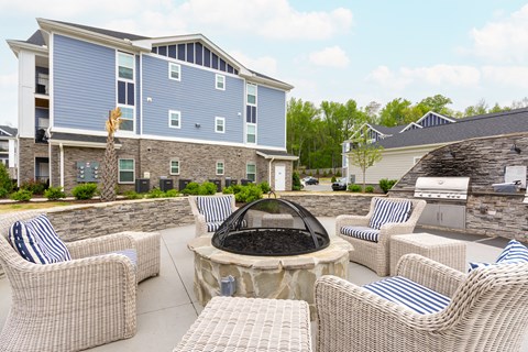 the patio has a fire pit and chairs with blue and white striped pillows