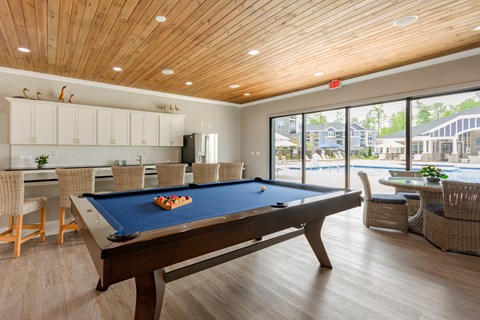 a pool table in a clubhouse with a view of a swimming pool