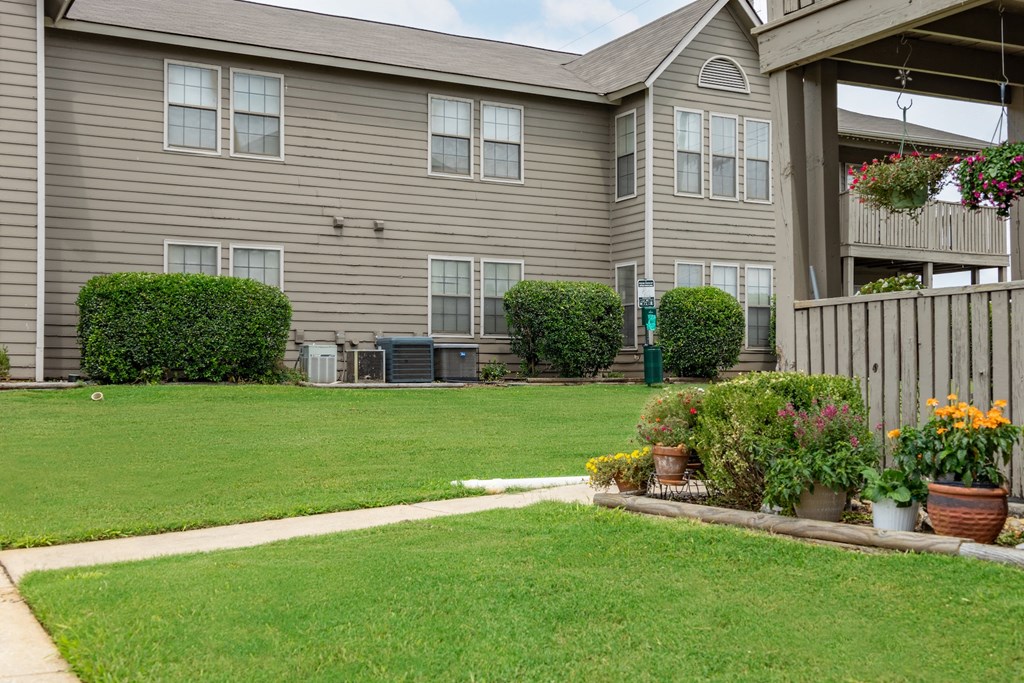 the yard of an apartment building with a lawn and potted plants