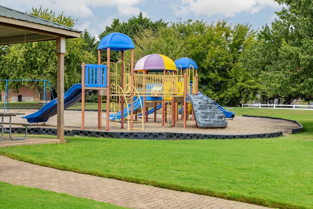 a playground with a swing set and slides in a park