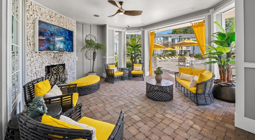 A patio with yellow couches and a fireplace.