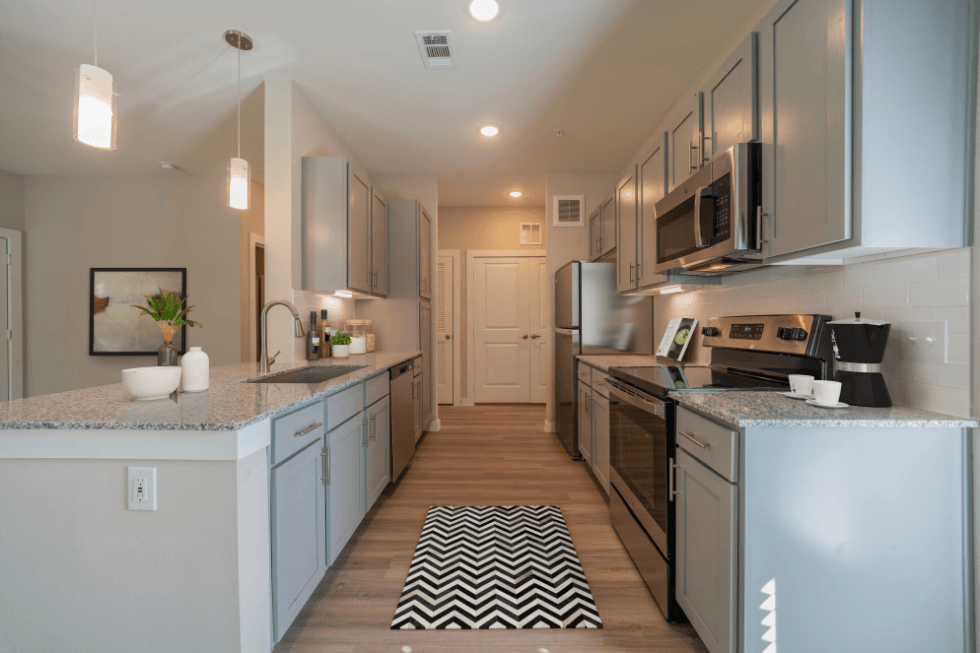 a large kitchen with stainless steel appliances and white counter tops