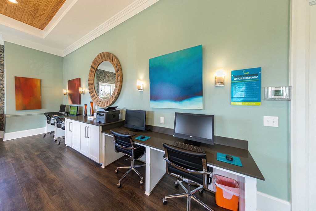 a room with a desk with computers and a mirror on the wall