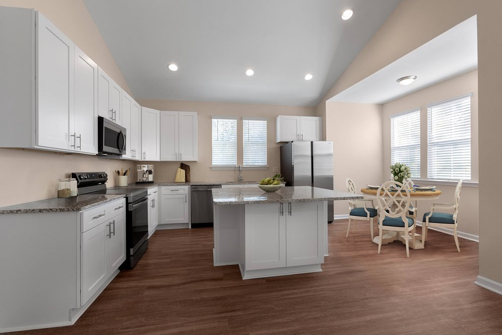 A kitchen with white cabinets and a wooden floor.