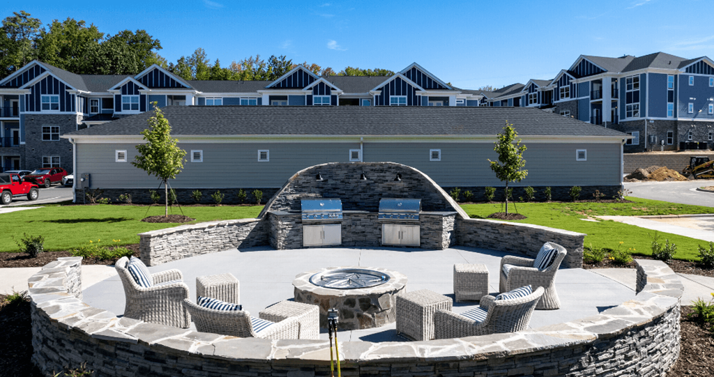 an outdoor patio with a fire pit in front of an apartment building