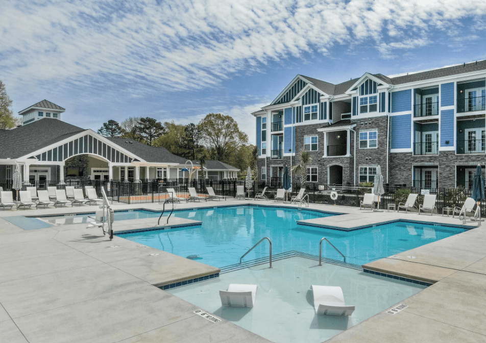 a large pool with chairs in front of a building