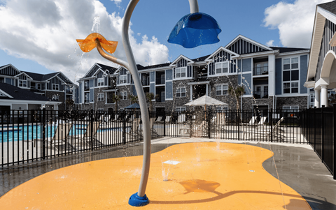 a water playground in front of a pool with apartments in the background