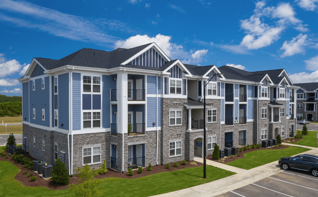 an apartment building on a street with a car in a parking lot