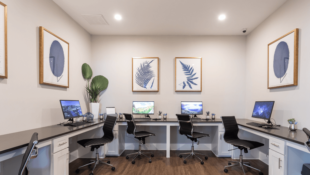 a room with four desks with computer monitors and chairs