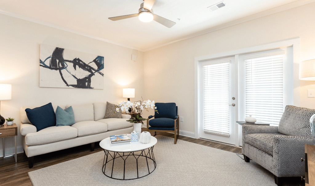 a living room with a couch and a chair and a ceiling fan