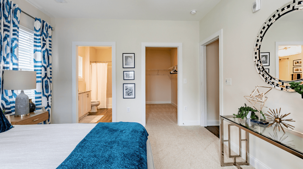 a bedroom with a bed and a mirror and a bathroom