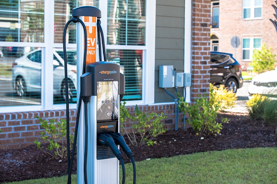 a gas pump in the grass in front of a building