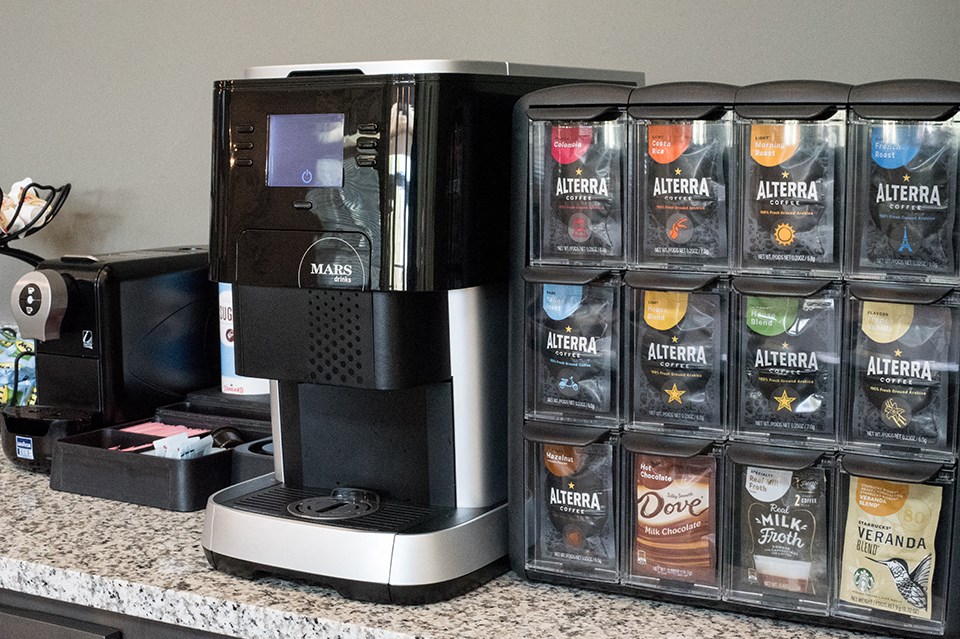 a coffee maker with several containers of coffee on a counter
