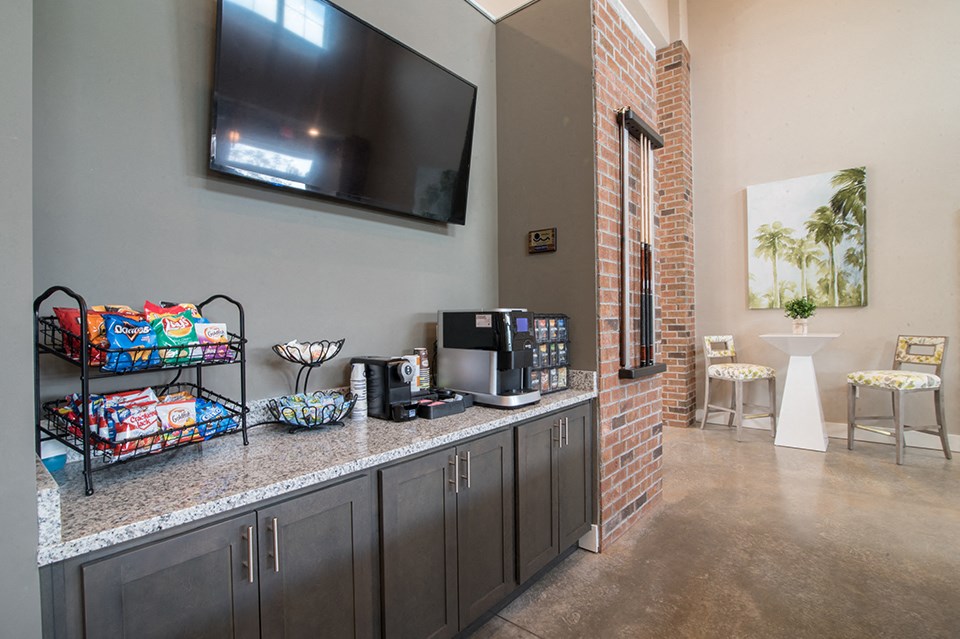 a kitchen with a counter with coffee machines and a television on the wall